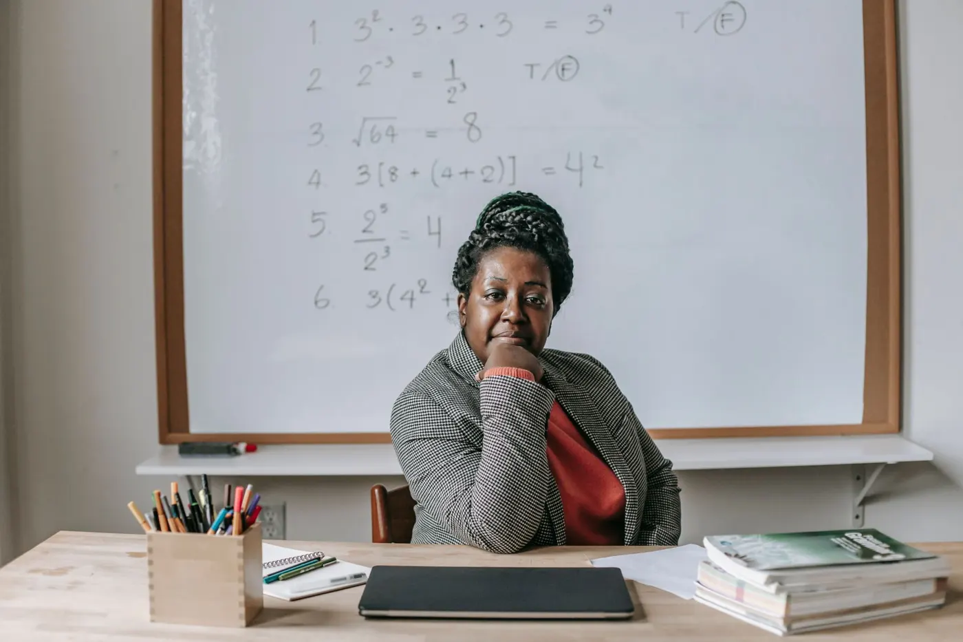 A teacher sitting at her desk in front of a whiteboard